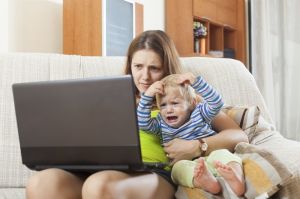 sorehead mother with crying baby working online with laptop at home