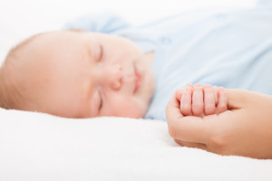 Cute sleeping newborn baby child holding mother hand