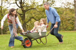 Parents Giving Children Ride In Wheelbarrow