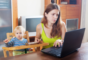 serious mother with baby using laptop