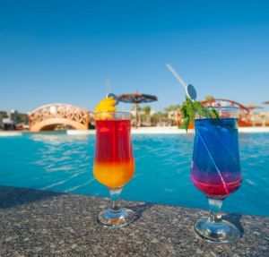 Two cocktail drinks by a tropical pool